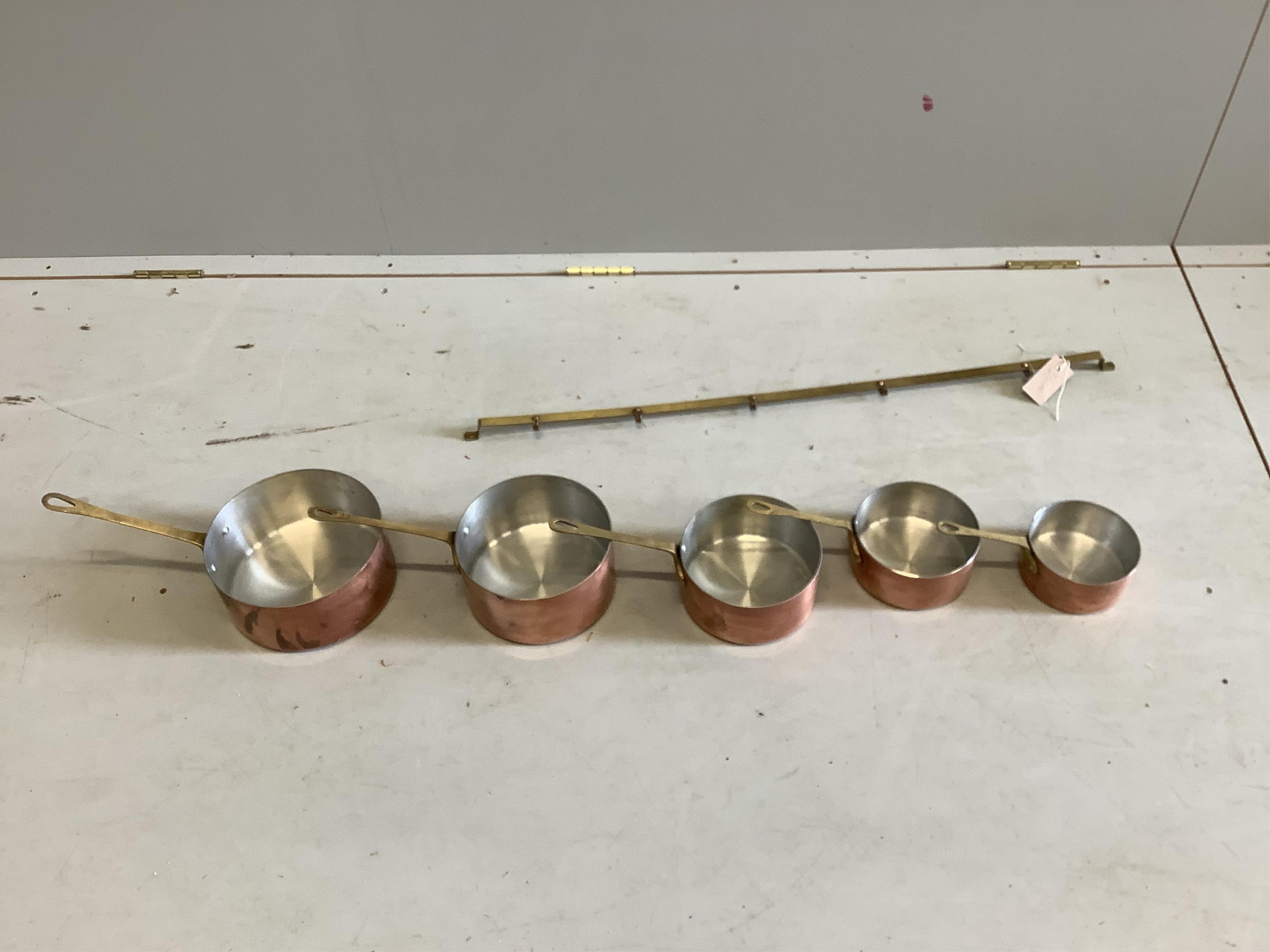 A graduated set of five circular copper pans with brass hanging rail, largest diameter 20cm. Condition - good